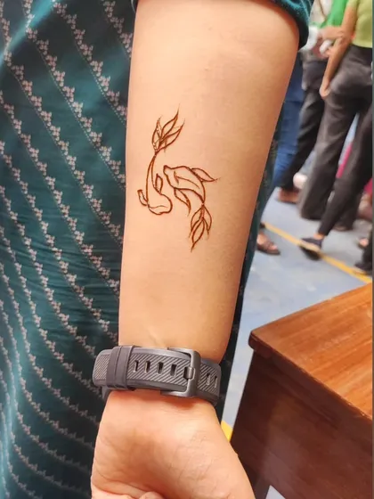 A simple and cute koi fish tattoo design on the wrist, perfect for a funfair or party.