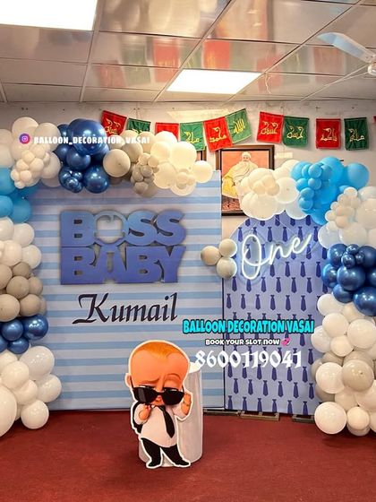Kumail's Boss Baby first birthday party. The setup features a striped backdrop, a balloon garland, and character cutouts, with a "one" neon sign.