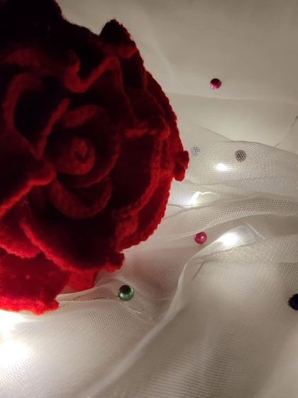A dramatic close-up of the center of the red rose, with fairy lights glowing in the background.