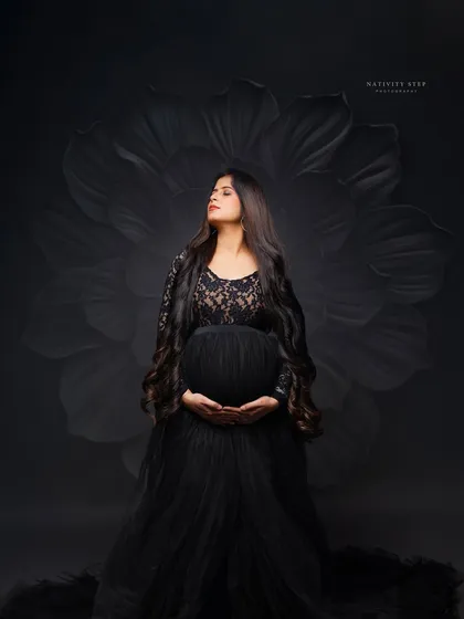 A powerful and elegant solo portrait. We use dramatic studio lighting and a classic black gown to sculpt the beautiful silhouette of the baby bump, creating a timeless piece of art.