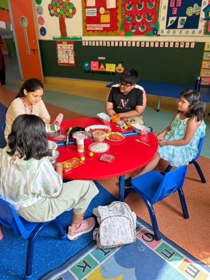 Students gather around the table to assemble their own bhel puri. This activity not only teaches culinary skills but also encourages social interaction and teamwork as they share ingredients and ideas.