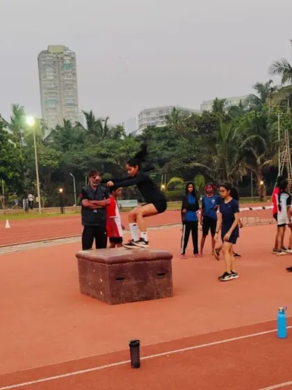 This is where dedication takes flight. An athlete performs a powerful box jump on our professional synthetic track, with our expert coach guiding her. This kind of plyometric training is key for building explosive strength and is a regular part of our athletics club sessions.