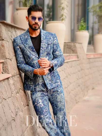 Leaning against a stone wall, this full-length shot of the blue splatter-print suit highlights its head-to-toe impact. This is for the man who refuses to blend in.