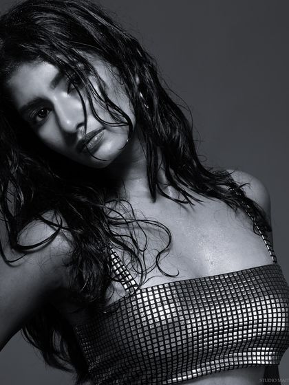 A close-up black and white portrait with a wet hair look. The intense lighting and direct gaze create a powerful and dramatic mood.