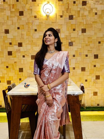 A full-length portrait of a woman in a beautiful silk saree, posing in a well-decorated interior space. This showcases both the person and the event's ambiance.
