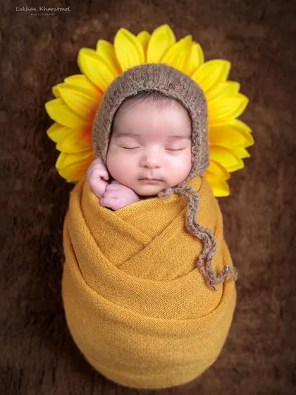 A bright and cheerful sunflower theme. The baby is wrapped in a warm yellow swaddle, with a large sunflower creating a beautiful halo effect.