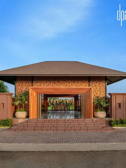 The magnificent entrance to the Dhanshree Farmhouse, a serene retreat and event space, features a grand portal framed in wood and set within a brick jali wall.