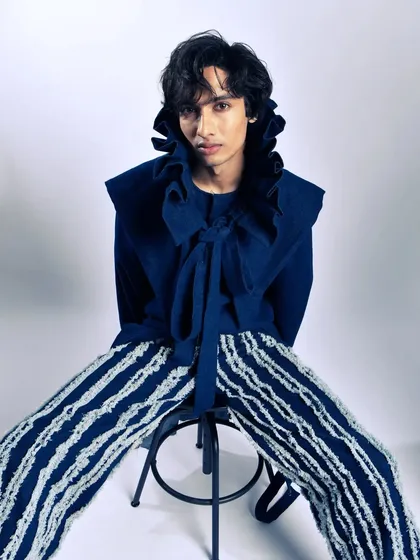 A direct, seated portrait that showcases the full impact of the high-collar design. The pose is simple, but the attitude is strong.