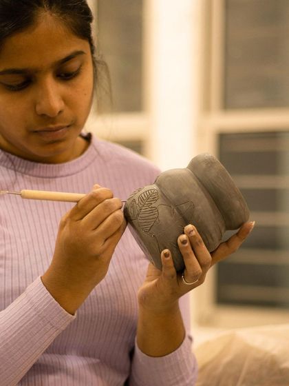A student carefully carves a leaf pattern into a planter. This is the first step in the Mishima inlay process.