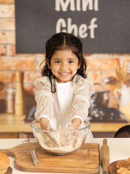 A joyful moment in the mini kitchen. This little chef's bright smile shows just how much fun a themed photoshoot can be.