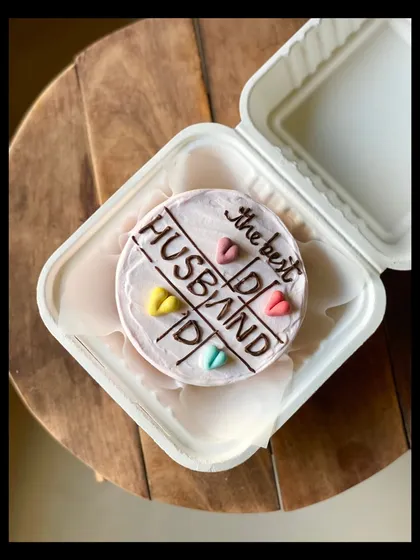 A sweet cake for "the best HUSBAND," designed with a tic-tac-toe theme and colorful hearts. It's a playful way to show your love and appreciation.