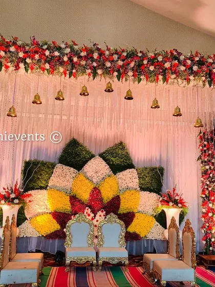 A colorful stage setup featuring a large lotus design made from yellow, red, and white flowers. This backdrop is perfect for a wedding or reception, adding a touch of traditional grandeur.