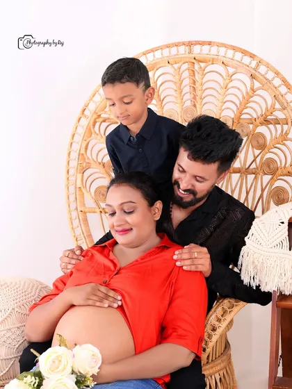 A heartwarming family portrait in our bohemian-themed studio. The older son joins his parents, who are seated on a peacock chair.