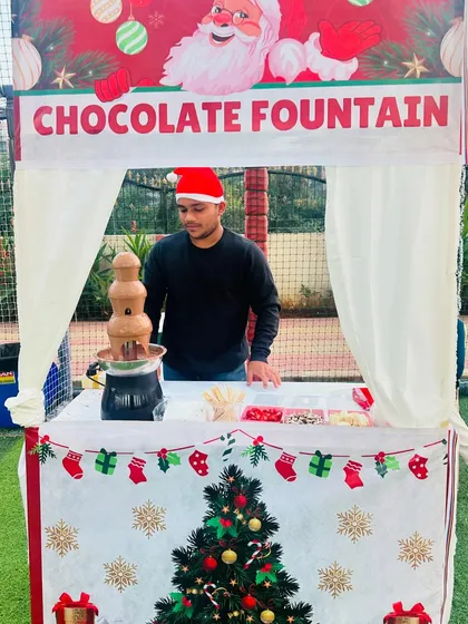 Our staff member, dressed for the occasion in a Santa hat, manages the chocolate fountain at a Christmas party, ensuring everything runs smoothly.