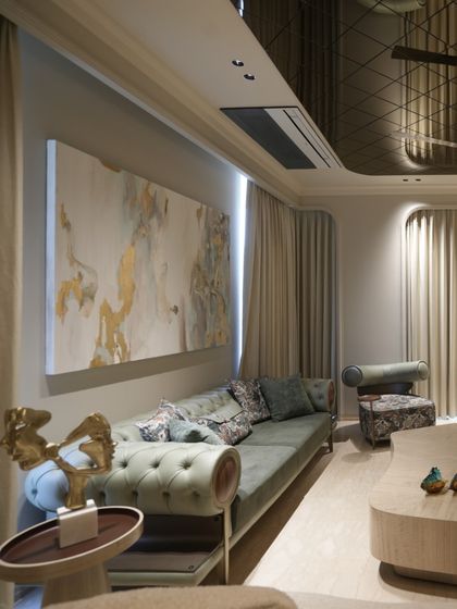 A side view highlighting the custom abstract art and the elegant silhouette of the olive green sofa. The lighting from above and behind the painting creates a soft, ambient glow.