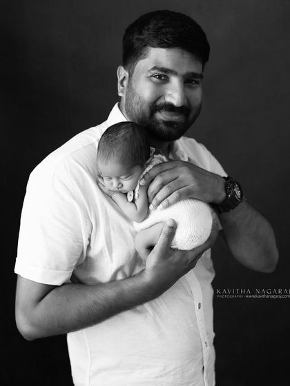 A father holds his newborn, a quiet moment of bonding. This black and white portrait is a timeless tribute to the special connection between a dad and his baby.