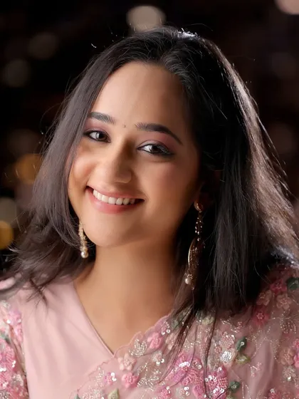 A close-up beauty shot focusing on the model's happy expression and the delicate details of her makeup and saree. The bokeh background adds a touch of magic.