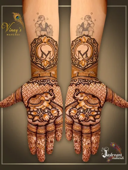 A grand design for a family member, featuring the initial 'M' on both wrists, topped with a portrait of a deity and surrounded by elephants on the palms.