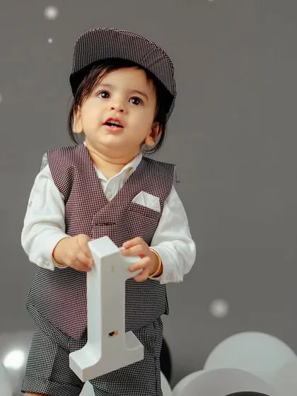 Dressed up for his first birthday. This little gentleman looks so sharp in his vest and cap, ready to celebrate his big milestone.
