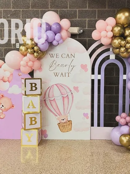 Combining two favorite themes, this "We Can Bearly Wait" setup features a hot air balloon element. The pastel pink and purple balloon garlands, custom backdrops, and 'BABY' blocks come together for a whimsical and adorable baby shower.