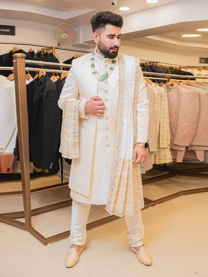 For the groom who wants a timeless and royal look. This classic ivory sherwani features delicate gold embroidery, a matching stole, and elegant accessories. We help you get the complete dulha look for your big day.