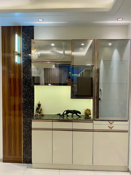 This crockery unit uses a mix of wood paneling, black granite, and reflective glass shutters to create a sophisticated and modern storage piece.