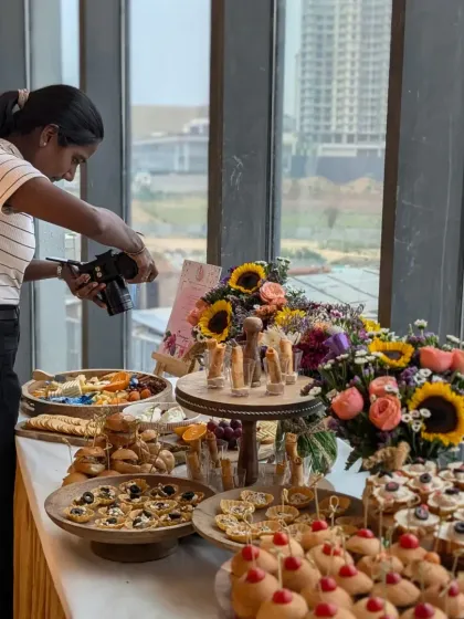 A wide shot of the full catering spread at the Varnya salon launch. This photo captures the variety of canapés, the beautiful floral arrangements, and the overall festive ambiance.