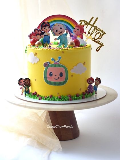 A bright and happy single-tier Cocomelon cake. This Chocolate Orange cake is covered in yellow buttercream and decorated with all the main characters and a rainbow topper.