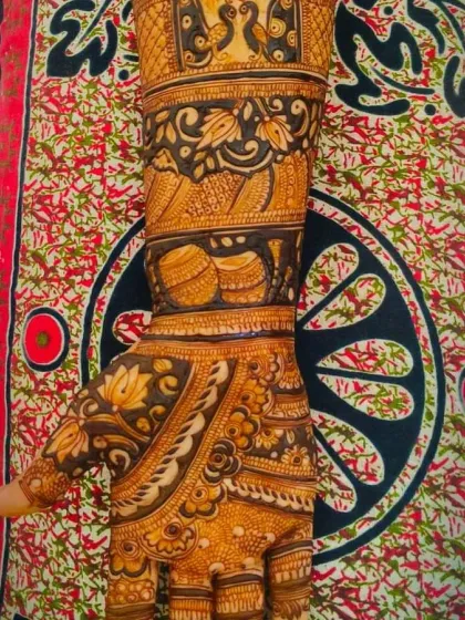 A close up showing the detail in a traditional design, with kalash (pots), peacocks, and lotus flowers, all symbols of prosperity and beauty.