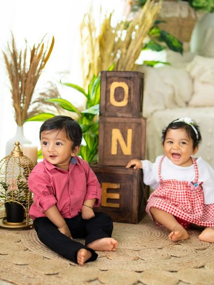 Two happy toddlers celebrating their first birthday together. The natural, bohemian-style setup is perfect for a relaxed and joyful shoot.