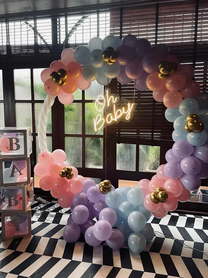 This pastel-themed baby shower decoration features a circular balloon arch in soft pink, purple, and blue. I added an "Oh Baby" neon sign for a modern touch and "BABY" blocks to complete the photo corner.