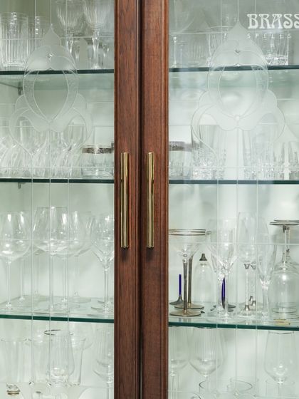 The Kiah CL Profile Pulls provide a sleek and substantial handle for these display cabinets, with the polished brass finish glowing against the dark wood.