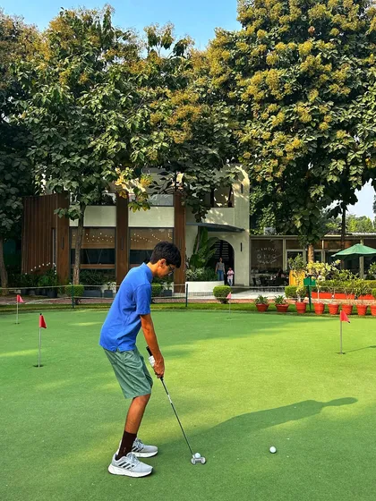 A young golfer lines up his putt on the practice green, showing great focus and form.
