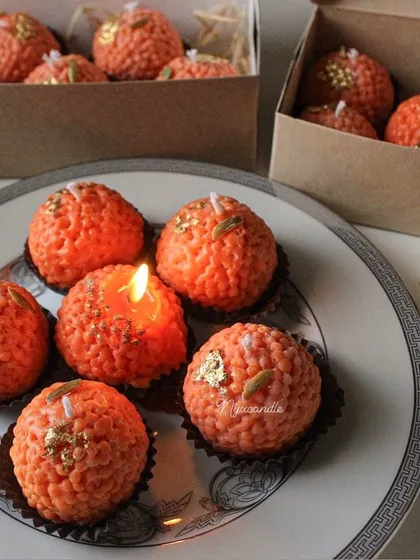 A plate of my motichoor ladoo candles, one of them lit to show it in action. They look incredibly realistic and are always a conversation starter.