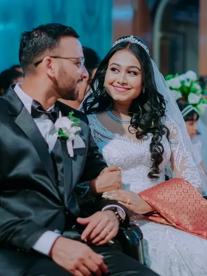 A candid moment of the couple seated during the church ceremony, sharing an intimate and loving glance.