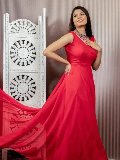 A model looking elegant in a simple, flowing red gown with a long train. This is a perfect rental for a pre-wedding shoot or a classic evening event.