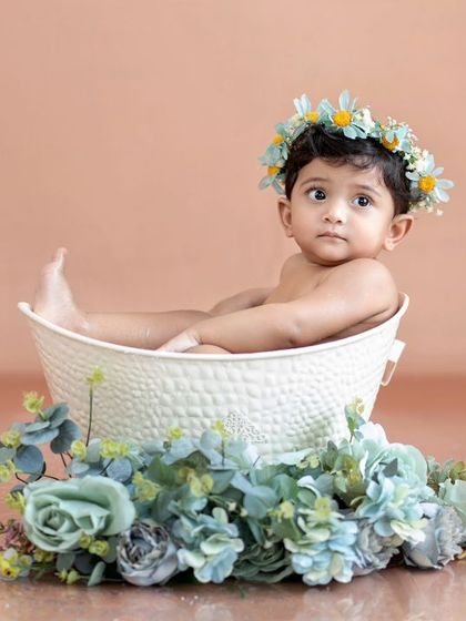 This little one is relaxing in her tub, surrounded by blue flowers and her ducky friends.
