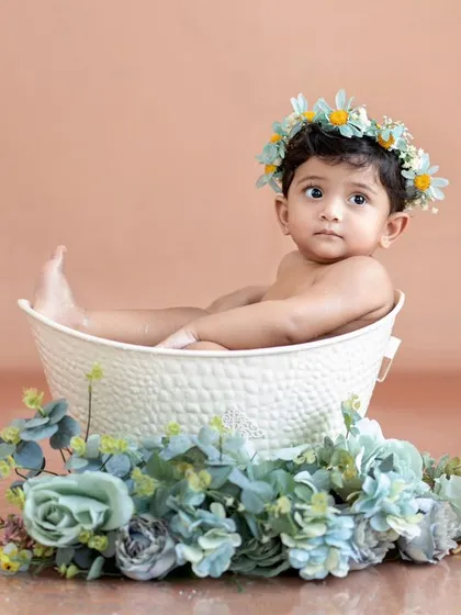 This little one is relaxing in her tub, surrounded by blue flowers and her ducky friends.