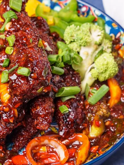 A close up of our Safeer Chongqing Chicken. This dish features crispy chicken tossed in a spicy and flavourful sauce with fresh vegetables like broccoli and bell peppers.