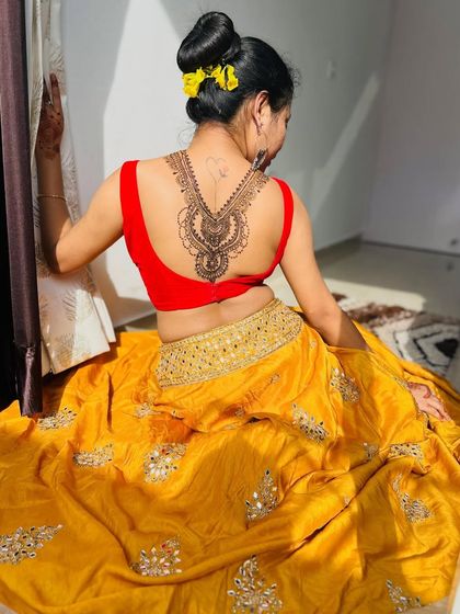 A beautiful shot of the client posing with her back mehndi. The design flows beautifully with the lines of her body.