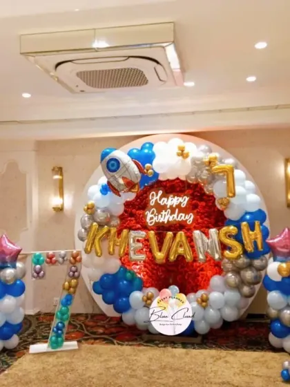 An exciting space-themed birthday party featuring a rocket ship, a custom backdrop with a red shimmer panel, and balloon pillars.