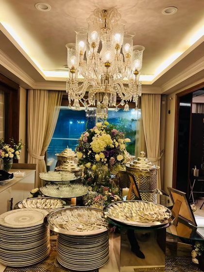 A stunning in-home buffet arrangement under a grand chandelier. This demonstrates how I can transform a private residence into a venue for a luxurious, fully catered event with multi-tiered displays and elegant serveware.