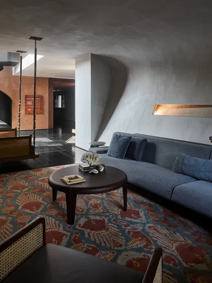 An intimate seating area in the Baid Residence, featuring a curved custom sofa and a traditional Indian swing. The organic forms of the architecture and furniture create a soft, cocoon-like space.