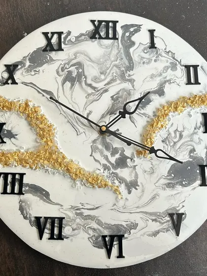 A close-up of a black, white, and grey marble clock with gold accents, showing the intricate fluid patterns.
