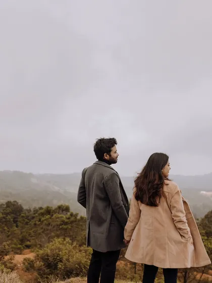 The couple holding hands and looking out at the vast, misty mountain range, symbolizing the start of their journey together.