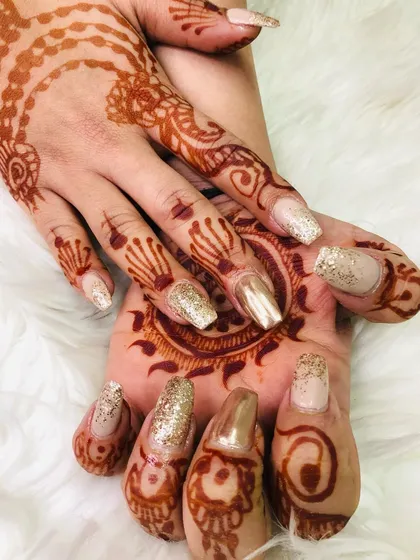 Another angle of these beautiful bridal nails. You can see how the gold glitter catches the light, making the detailed henna work on her hands and palm stand out even more.