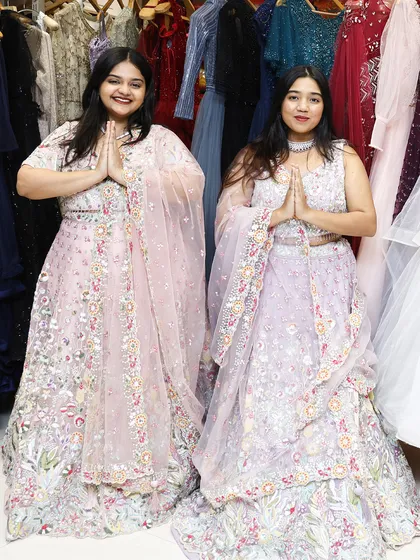 A cute "namaste" pose from two clients in matching pastel lehengas, showing the fun side of dressing up together.