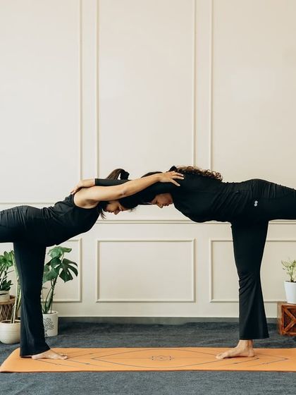 A shared Virabhadrasana III (Warrior III) pose, where balance is found through connection. This pose builds focus, stability, and a sense of shared energy.