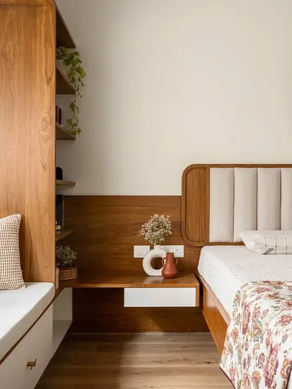 The 'Palaash' master bedroom features a custom headboard with two upholstered panels, a bay window seat, and an integrated bedside table.