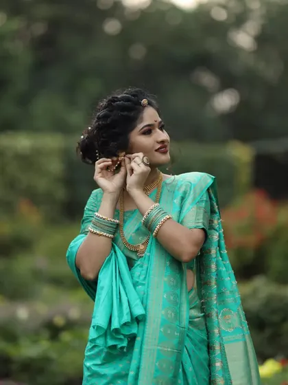 Adjusting the earring on her traditional look, this client embodies the grace of a Marathi woman. The makeup is soft, with a focus on her expressive eyes.